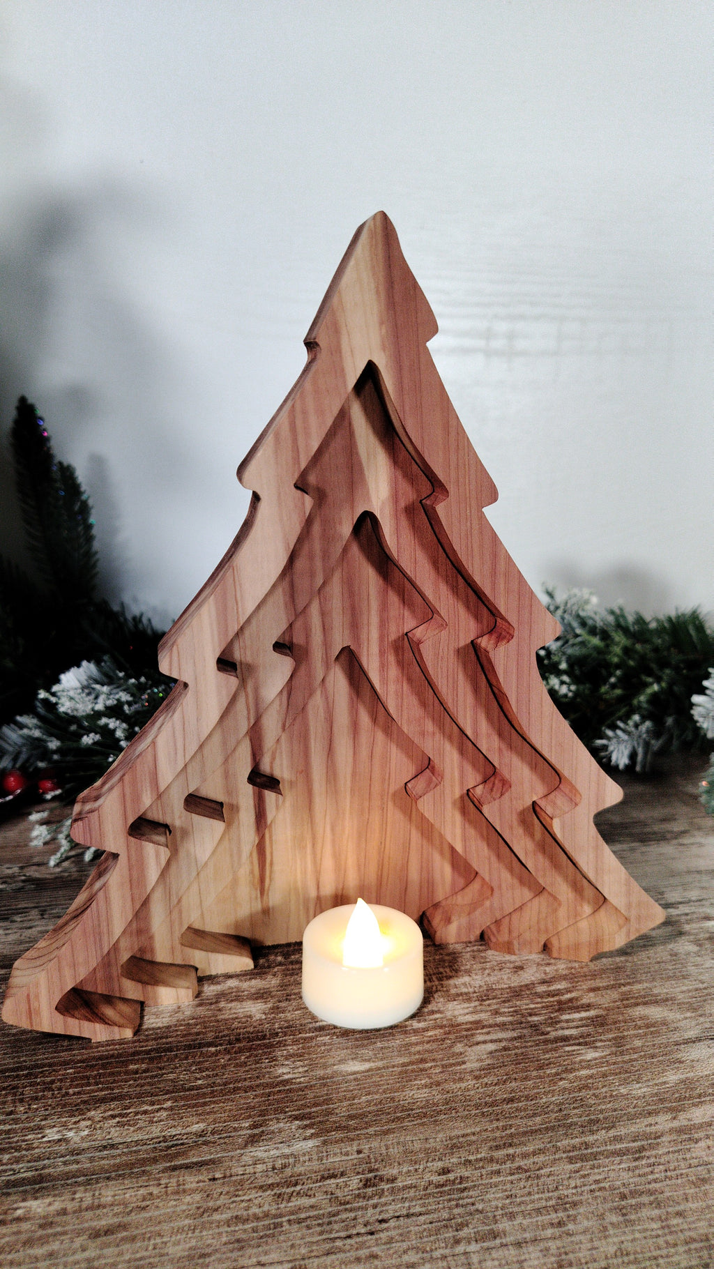 Wooden Christmas tree decoration with a candle inside on a wooden surface.