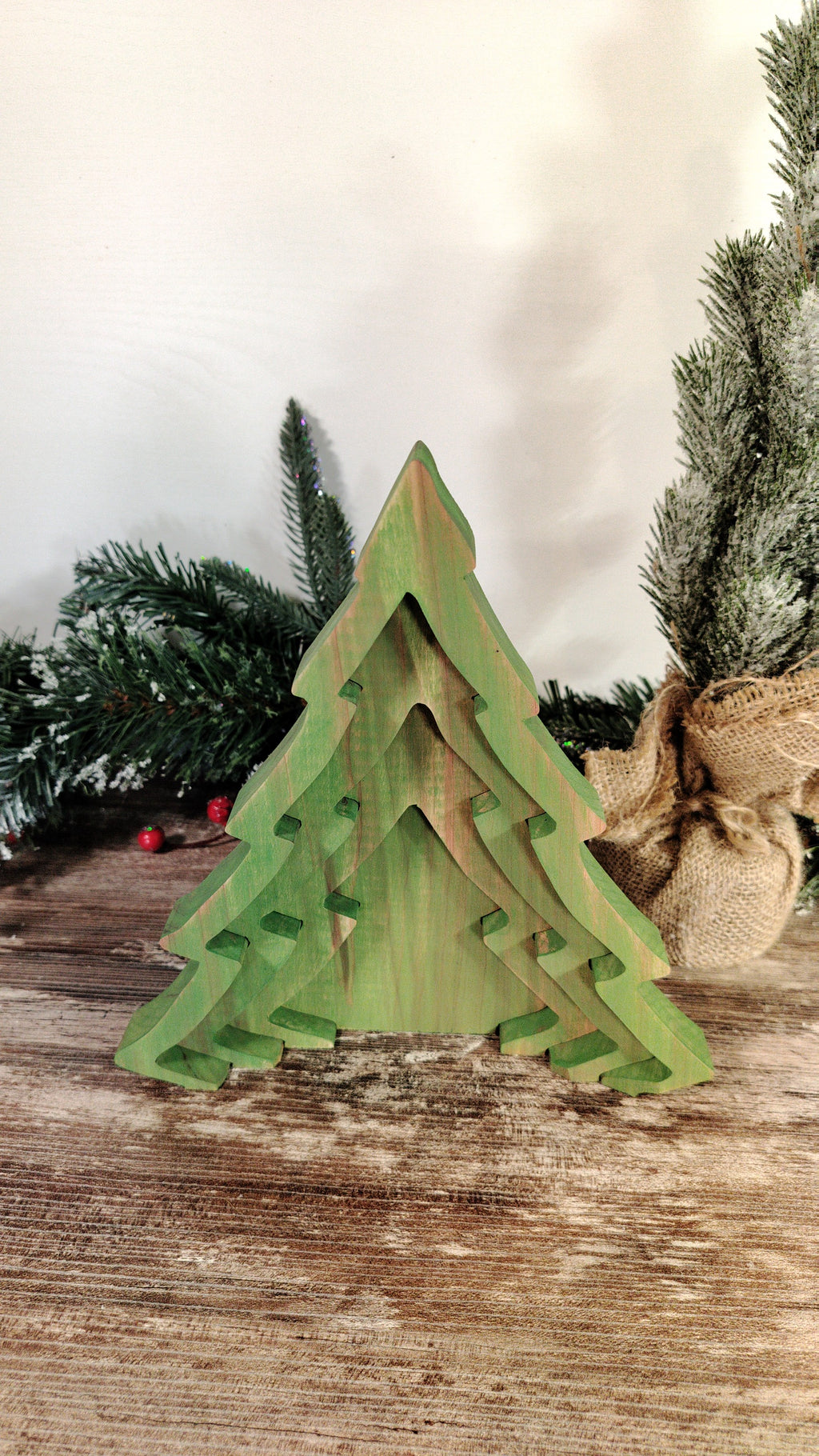 Green wooden Christmas tree decoration on a wooden surface with a blurred background