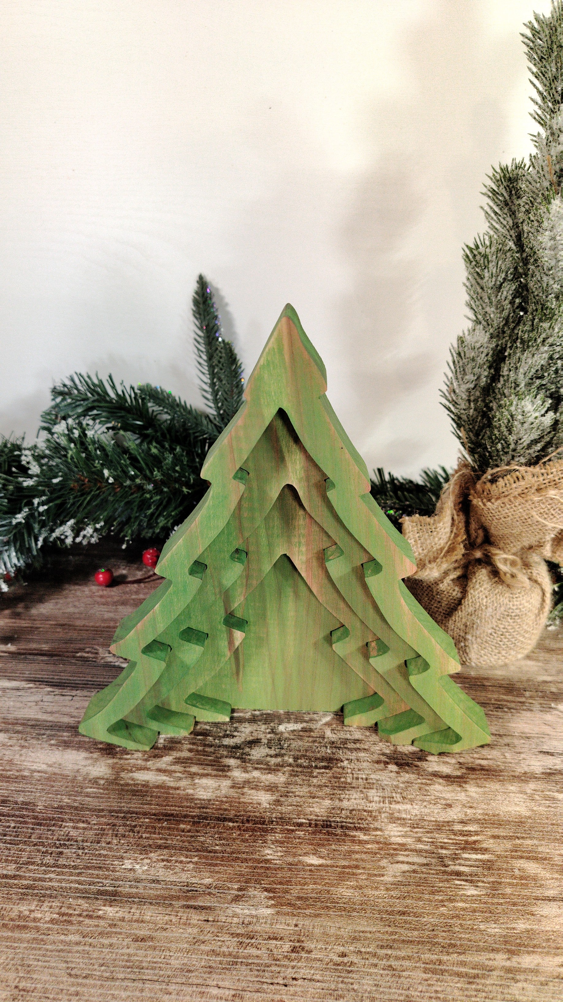 Green wooden Christmas tree decoration on a wooden surface with a blurred background