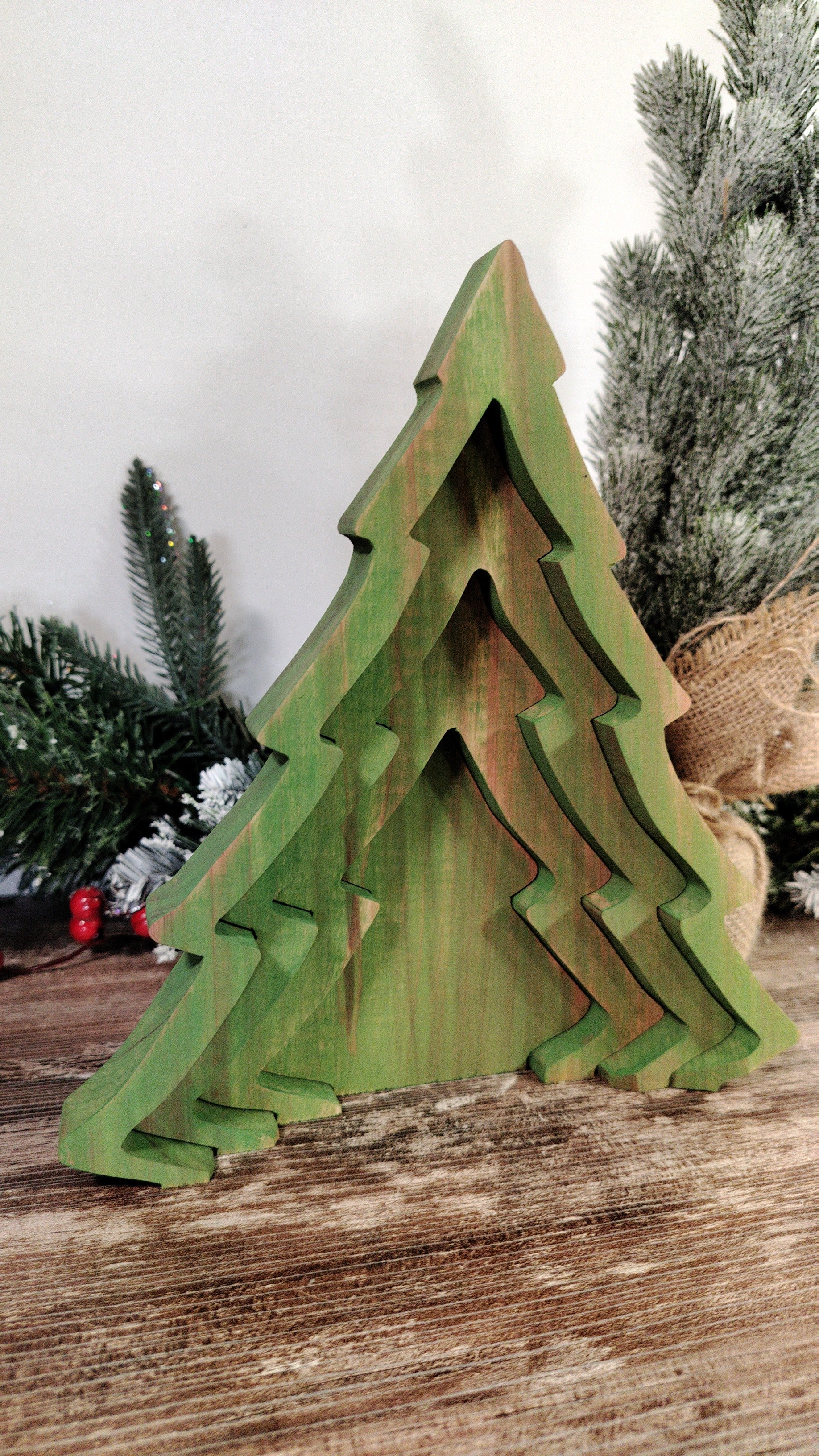 Green wooden Christmas tree decoration on a wooden surface with a blurred background